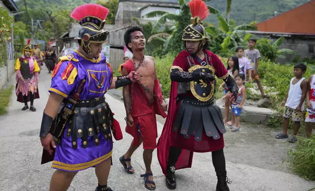 Performers dressed as Roman soldiers push a man playing the role of Barabbas during a reenactment of the passion and sufferings of Jesus Christ on Maundy Thursday in Paete town, Laguna province, Philippines, April 17, 2025. (AP Photo/Aaron Favila)