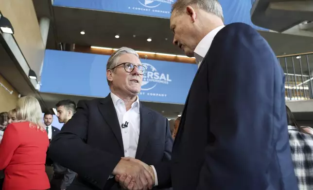 British Prime Minister Keir Starmer, left, shakes hand with President of Comcast Corporation Michael Cavanagh at an announcement that U.S. media giant Comcast Corp will build its first Universal theme park and resort in Europe, opening in 2031, during a visit to Bedford, north of London, Wednesday April 9, 2025. (John Sibley/Pool Photo via AP)