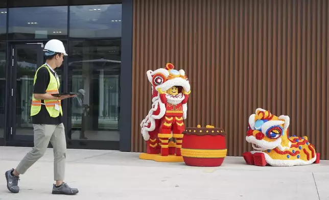 A worker walks past Lego characters in Vietnamese traditional lion dance costumes displayed at Lego factory in Binh Duong, Vietnam Wednesday, April 2, 2025. (AP Photo/Hau Dinh)
