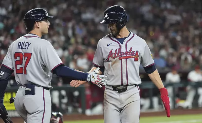 Atlanta Braves' Eli White, right, celebrates his run scored against the Arizona Diamondbacks with Braves' Austin Riley (27) during the fifth inning of a baseball game Sunday, April 27, 2025, in Phoenix. (AP Photo/Ross D. Franklin)