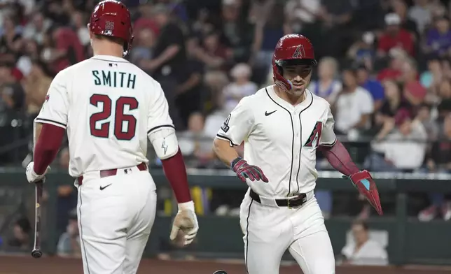 Arizona Diamondbacks' Corbin Carroll, right, celebrates his run scored against the Atlanta Braves with Diamondbacks' Pavin Smith (26) during the first inning of a baseball game Sunday, April 27, 2025, in Phoenix. (AP Photo/Ross D. Franklin)