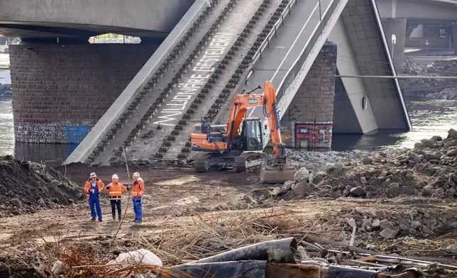 FILE - Experts stand in front of an excavator on the partially collapsed Carola Bridge on the Neustadt side during works, in Dresden, Germany, Thursday Jan. 30, 2025. (Robert Michael/dpa via AP, File)