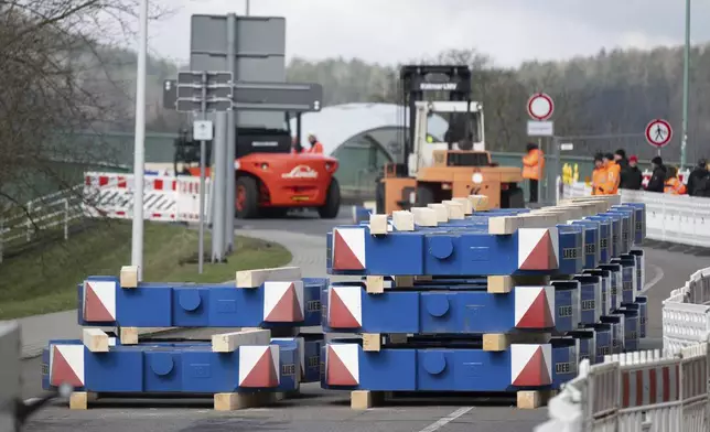 Weights are placed at the foot of the closed Elbe bridge as part of a load test, during a the three-day load test intended to show that the Elbe crossing can be reopened to traffic, in Bad Schandau, Germany, Tuesday April 1, 2025. (Sebastian Kahnert/dpa via AP)