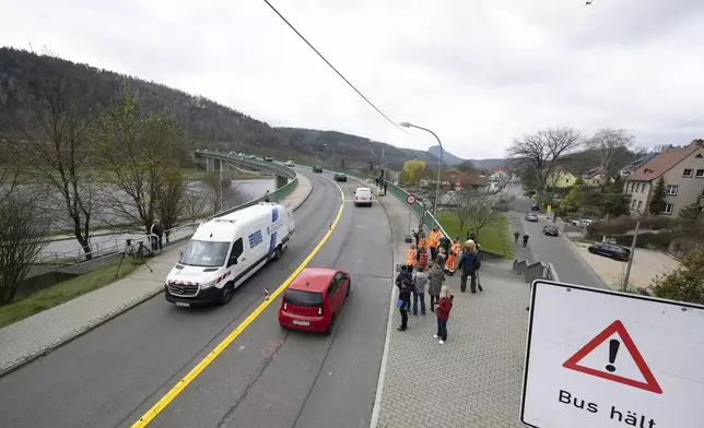 Passers-by and cars cross the Elbe bridge in Bad Schandau to mark the opening to traffic, in Dresden, Germany, Thursday April 10, 2025. (Sebastian Kahnert/dpa via AP)