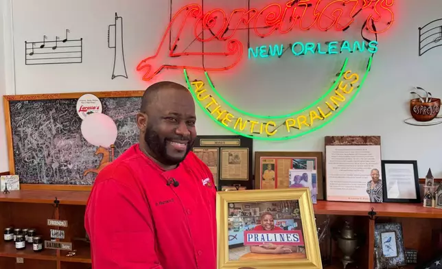 Robert Harrison III, Loretta's Pralines president and CEO, holds a portrait of his mother on Tuesday, April 22, 2025, as he prepares thousands of pralines for the New Orleans Jazz and Heritage Festival. (AP Photo/Jack Brook)