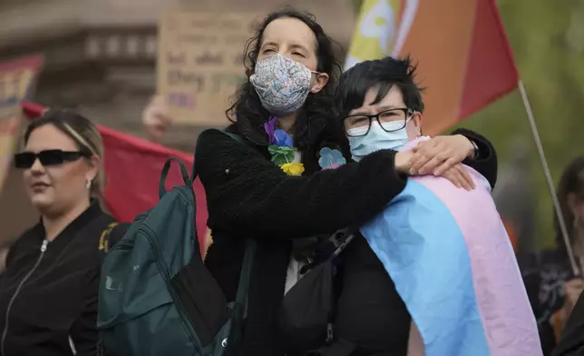 A couple hug as they take part in a rally organised by trans rights groups, trade unions, and community organisations following the Supreme Court ruling on the definition of a woman in equalities law, at Parliament Square, central London, Saturday April 19, 2025. (AP Photo/Alastair Grant)