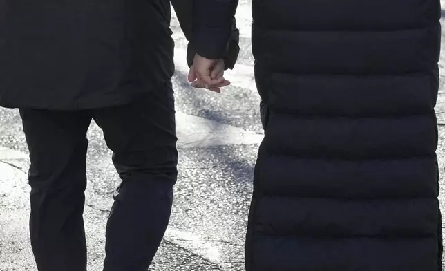 FILE - A couple holds hands while crossing the street during a cold morning in Beijing, China on Friday, Jan. 10, 2025. (AP Photo/Aaron Favila, File)