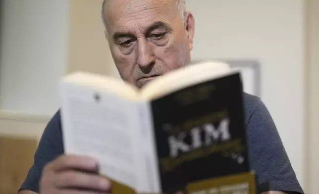 Yunice Abbas, one of the men accused in the 2016 armed robbery of Kim Kardashian , reads the book "I Sequestered Kim Kardashian" during an interview with the Associated Press, Tuesday, April 22, 2025 in Paris. (AP Photo/Thibault Camus)