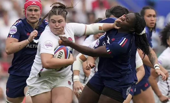 England's Maud Muir, center, is challenged by Yllana Brosseau of France during the Women's Six Nations rugby union match at Twickenham stadium in London, Saturday, April 26, 2025. (AP Photo/Alastair Grant)