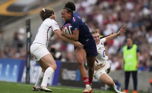 Kelly Arby of France, centre, breaks away from a challenged by England's Emma Sing, to score a try during the Women's Six Nations rugby union match at Twickenham stadium in London, Saturday, April 26, 2025. (AP Photo/Alastair Grant)