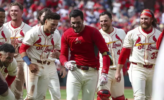 St. Louis Cardinals' Nolan Arenado, center, runs from teammates as they celebrate after his walkoff solo home run during the ninth inning of a baseball game against the Milwaukee Brewers, Saturday, April 26, 2025, in St. Louis. (AP Photo/Scott Kane)