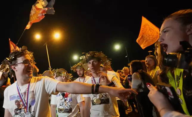 People welcome 80 Serbian university students who cycled more than 1,300 kilometers (780 miles) during last week, from Novi Sad to Strasbourg, France, to draw EU attention to their months-long protests against corruption, in Novi Sad, Serbia, Tuesday, April 22, 2025. (AP Photo/Darko Vojinovic)