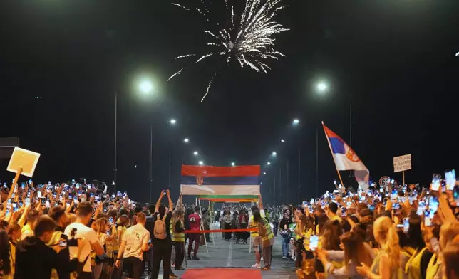 People welcome 80 Serbian university students who cycled more than 1,300 kilometers (780 miles) during last week, from Novi Sad to Strasbourg, France, to draw EU attention to their months-long protests against corruption, in Novi Sad, Serbia, Tuesday, April 22, 2025. (AP Photo/Darko Vojinovic)