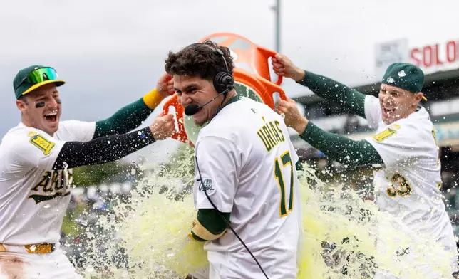 Athletics' Luis Urías (17) gets doused with Gatorade by teammates after hitting a walk-off home run during the 10th inning of a baseball game against the Chicago White Sox, Sunday, April 27, 2025, in West Sacramento, Calif. (AP Photo/Sara Nevis)