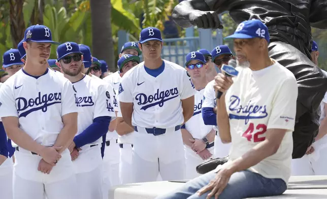 Los Angeles Dodgers' Shohei Ohtani, center, and teammates listen to former NBA player Kareem Abdul-Jabbar during an event to commemorate Jackie Robinson Day before a baseball game against the Colorado Rockies Tuesday, April 15, 2025, in Los Angeles. (AP Photo/Damian Dovarganes)
