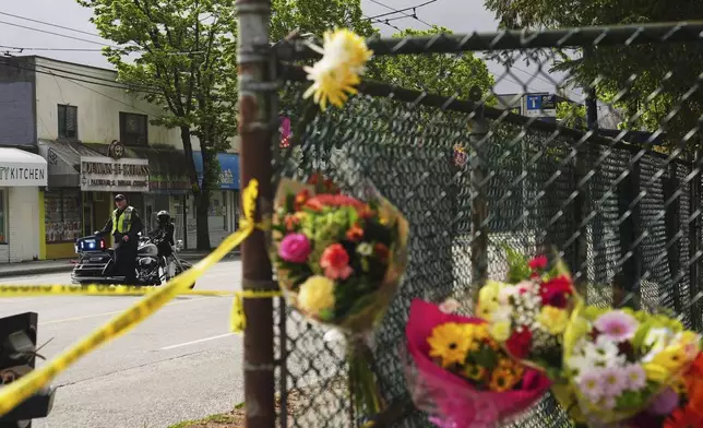 A Vancouver Police officer monitors the scene as a memorial of flowers grows the day after a driver killed multiple people during a Filipino community festival Sunday, April 27, 2025, in Vancouver, British Columbia. (AP Photo/Lindsey Wasson)