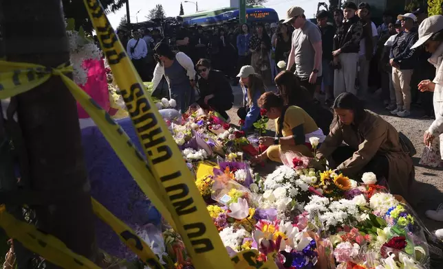 Visitors pay their respects at a memorial after a vehicle drove into a crowd during a Filipino heritage festival in Vancouver, British Columbia, Sunday, April 27, 2025. (AP Photo/Lindsey Wasson)