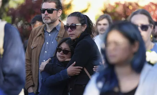 Two women embrace at a memorial after a vehicle drove into a crowd during a Filipino heritage festival in Vancouver, British Columbia, Sunday, April 27, 2025. (AP Photo/Lindsey Wasson)