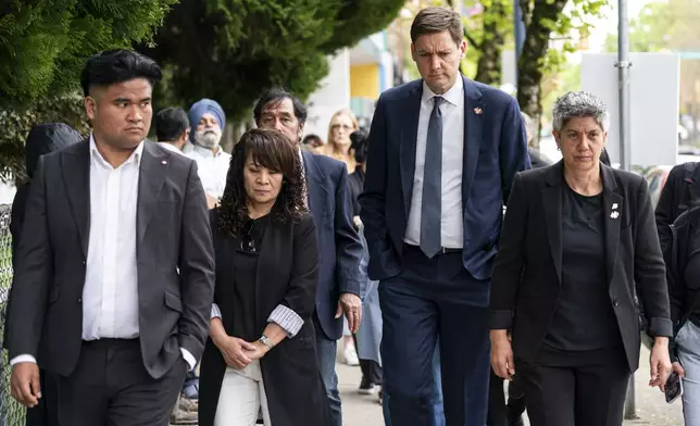 British Columbia Premier David Eby, second from right, and Member of the Legislative Assembly of B.C., Mable Elmore, walk with members of the Filipino community to a press conference after a vehicle drove into a crowd during a Lapu Lapu Day festival in Vancouver, British Columbia, Sunday, April 27, 2025. (Rich Lam/The Canadian Press via AP)