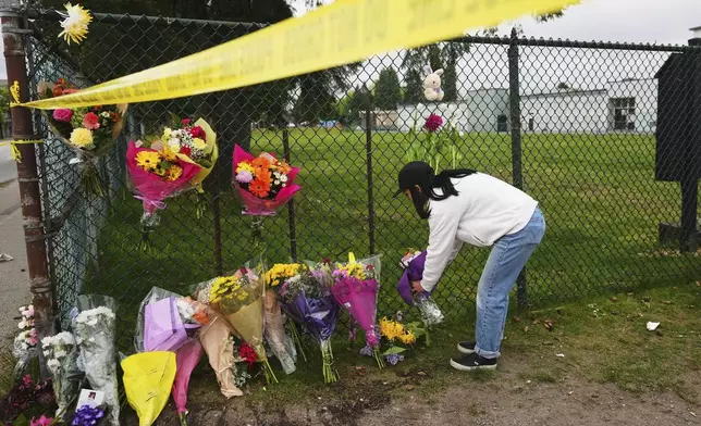 Sarah Edmilao, a member of the Filipino community who says friends had attended earlier in the day, places flowers at a growing memorial near a site the day after a driver killed multiple people during a Filipino festival Sunday, April 27, 2025, in Vancouver, British Columbia. (AP Photo/Lindsey Wasson)