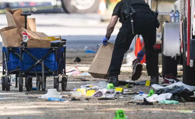 A member of the Vancouver Police forensics team picks up a shoe while investigating the scene where a vehicle drove into a crowd Saturday night at a street festival, in Vancouver, British Columbia, Sunday, April 27, 2025. (Rich Lam/The Canadian Press via AP)