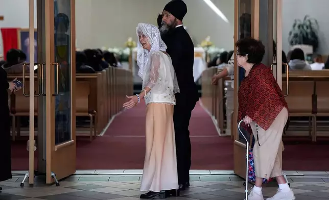 NDP Leader Jagmeet Singh walks with Rosita Taruc, front centre, as he arrives to attend mass at St. Mary's Parish, after multiple people that were stuck by a car were killed on Saturday at a Filipino heritage festival in Vancouver, British Columbia, Sunday, April 27, 2025. Darryl Dyck/The Canadian Press via AP)