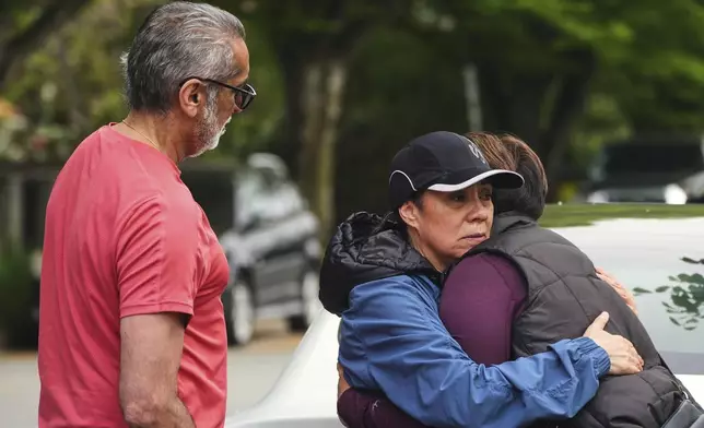 Esperanza Bermudez, center, who lives across the street from the scene, is comforted by friends Ronnie Claire, right, and Manjit Claire, the morning after a driver killed multiple people during a Filipino community festival Sunday, April 27, 2025, in Vancouver, British Columbia. (AP Photo/Lindsey Wasson)