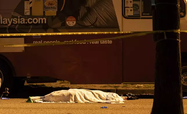 A victim covered with a cloth lies near a food truck after a car drove into a crowd at the Lapu Lapu Festival in Vancouver, British Columbia, Saturday, April 26, 2025. (Rich Lam/The Canadian Press via AP)