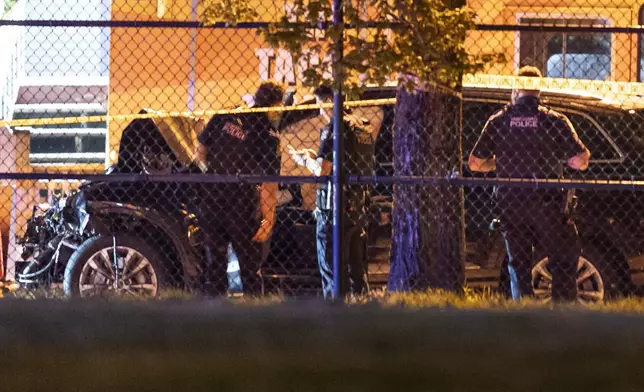 Vancouver police examine a black car suspected to be involved at a scene after a vehicle drove into a crowd at the Lapu Lapu Festival in Vancouver, British Columbia, Saturday April 26, 2025. (Rich Lam/The Canadian Press via AP)
