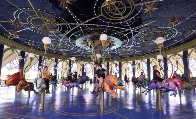 Guests ride the Constellation Carousel in Celestial Park in Epic Universe at Universal Resort Orlando Thursday, April 10, 2025, in Orlando, Fla. (AP Photo/John Raoux)