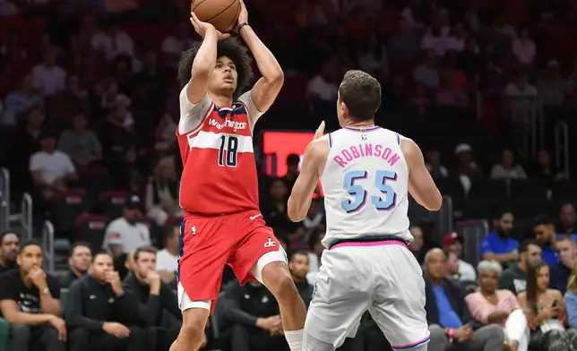 Washington Wizards forward Kyshawn George (18) shoots over Miami Heat forward Duncan Robinson (55) during the first half of a basketball game, Sunday, April 13, 2025, in Miami. (AP Photo/Michael Laughlin)