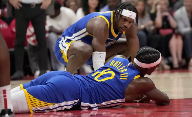 Golden State Warriors guard Buddy Hield (7) checks on forward Jimmy Butler III (10) after a collision with Houston Rockets' Amen Thompson under the basket during the first half of Game 2 of an NBA basketball first-round playoff series against the Houston Rockets in Houston, Wednesday, April 23, 2025. (AP Photo/Karen Warren)