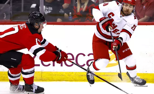 Carolina Hurricanes left wing William Carrier (28) passes the puck against New Jersey Devils defenseman Simon Nemec (17) during the second period of Game 3 of a first-round NHL hockey playoff series Friday, April 25, 2025, in Newark, N.J. (AP Photo/Noah K. Murray)