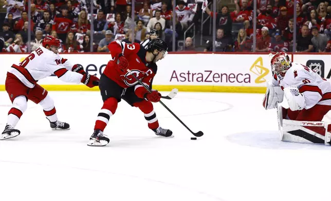 New Jersey Devils center Nico Hischier (13) scores against Carolina Hurricanes defenseman Sean Walker, left, and goaltender Frederik Andersen, right, during the first period of Game 3 of a first-round NHL hockey playoff series Friday, April 25, 2025, in Newark, N.J. (AP Photo/Noah K. Murray)