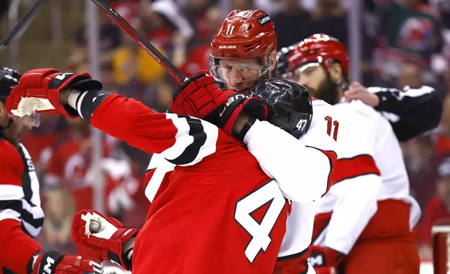 Carolina Hurricanes center Jordan Staal (11) puts New Jersey Devils center Paul Cotter (47) in a chokehold during the first period of Game 3 of a first-round NHL hockey playoff series Friday, April 25, 2025, in Newark, N.J. (AP Photo/Noah K. Murray)