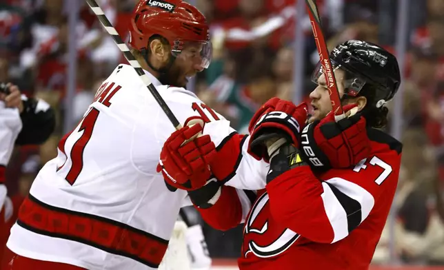 Carolina Hurricanes center Jordan Staal (11) and New Jersey Devils center Paul Cotter (47) fight during the first period of Game 3 of a first-round NHL hockey playoff series Friday, April 25, 2025, in Newark, N.J. (AP Photo/Noah K. Murray)