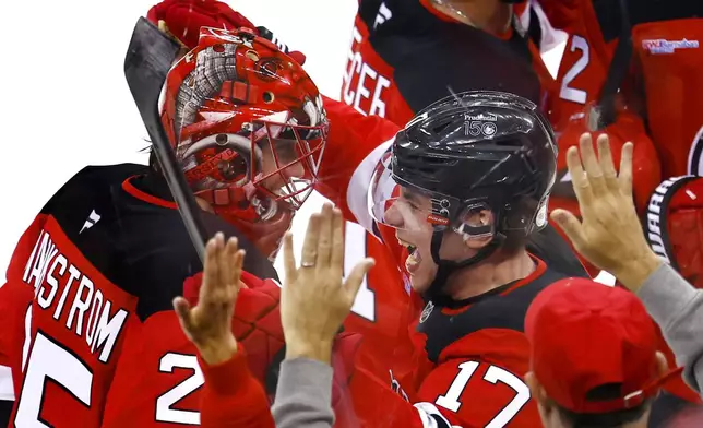 New Jersey Devils' Jacob Markstrom, left, and Simon Nemec (17) celebrate after defeating the Carolina Hurricanes in overtime of Game 3 in a first-round NHL hockey playoff series Friday, April 25, 2025, in Newark, N.J. (AP Photo/Noah K. Murray)