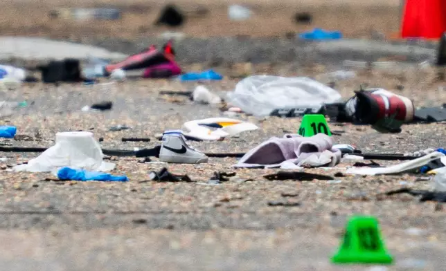 A small shoe lies among the debris and evidence markers on the street while police investigate after a vehicle drove into a crowd Saturday killing multiple people at a street festival, in Vancouver, British Columbia, Sunday, April 27, 2025. (Rich Lam/The Canadian Press via AP)