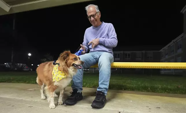 Carmine, of Waretown, and his dog Amber sit outside an evacuation center at Southern Regional High School during wildfires on Tuesday, April 22, 2025, near Stafford Township, N.J. (AP Photo/Chris Szagola)