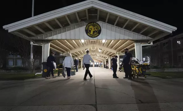 People head into an evacuation shelter at Southern Regional High School from wildfires on Tuesday, April 22, 2025, near Stafford Township, N.J. (AP Photo/Chris Szagola)