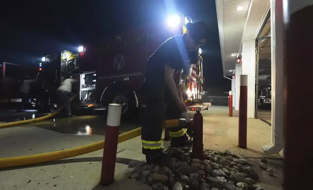 A Waretown volunteer firefighter helps prepare a firetruck to respond to a wildfire on Tuesday, April 22, 2025, in Waretown, N.J. (AP Photo/Chris Szagola)