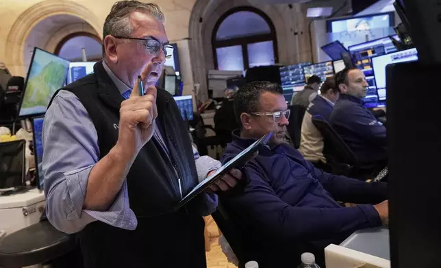 Trader John Bishop, left, works with colleagues on the floor of the New York Stock Exchange, Monday, April 21, 2025. (AP Photo/Richard Drew)
