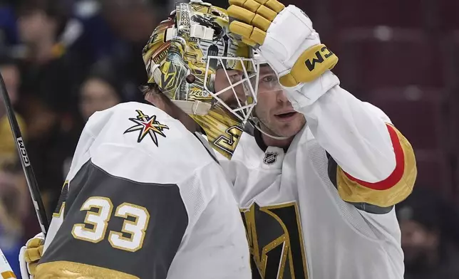 Vegas Golden Knights goalie Adin Hill, left, and Brayden McNabb celebrate after Vegas defeated the Vancouver Canucks in an NHL hockey game in Vancouver, British Columbia, Sunday, April 6, 2025. (Darryl Dyck/The Canadian Press via AP)