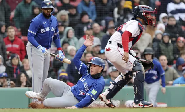 Toronto Blue Jays' Will Wagner, center, scores in the seventh inning of a baseball game past Boston Red Sox catcher Carlso Narvaez, right, Thursday, April 10, 2025, in Boston. (AP Photo/Jim Davis)