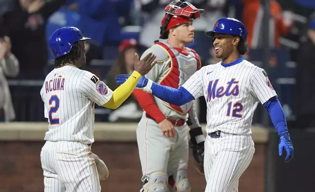 Philadelphia Phillies catcher J.T. Realmuto, center, looks away as New York Mets' Luisangel Acuña, left, celebrates with Francisco Lindor, right, after Lindor hit a three-run home run during the seventh inning of a baseball game Monday, April 21, 2025, in New York. (AP Photo/Frank Franklin II)