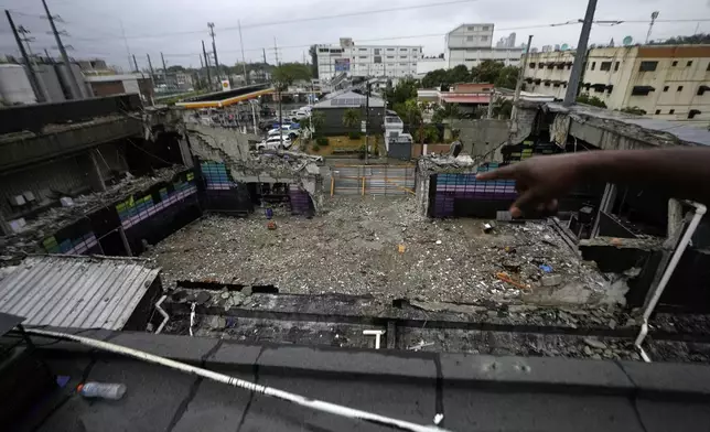 A person points to the inside of the Jet Set nightclub days after its roof collapsed, killing more than 200 people, in Santo Domingo, Dominican Republic, Friday, April 11, 2025. (AP Photo/Matias Delacroix)