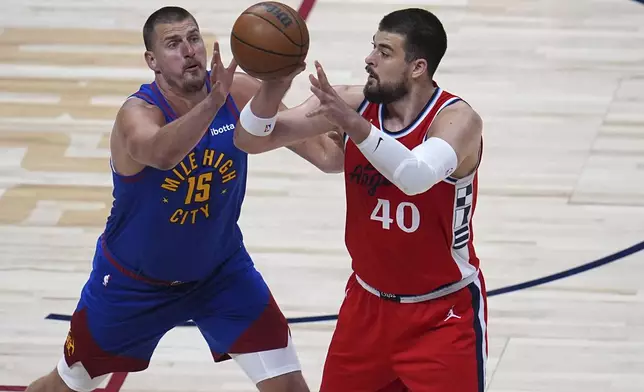 Los Angeles Clippers center Ivica Zubac, right, looks to pass the ball as Denver Nuggets center Nikola Jokic, left, defends in the first half of Game 1 of an NBA first-round playoff series Saturday, April 19, 2025, in Denver. (AP Photo/David Zalubowski)