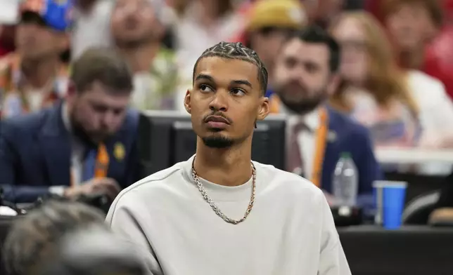 San Antonio Spurs' Victor Wembanyama watches Florida and Houston during the second half in the national championship at the Final Four of the NCAA college basketball tournament, Monday, April 7, 2025, in San Antonio. (AP Photo/Eric Gay)