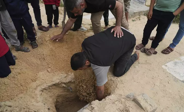 Fayez Zidan, lowers into the grave his 15-days-old premature infant Sila Zidane after she died at Nasser Hospital in Khan Younis, at the cemetery in Deir al-Balah, Gaza, on Wednesday, April 23, 2025. (AP Photo/Abdel Kareem Hana)