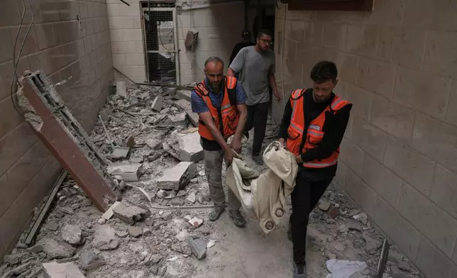 Palestinian civil defense workers carry the remains of a person killed during an Israeli airstrike on a residential building in Gaza City, Thursday, April 24, 2025. (AP Photo/Jehad Alshrafi)